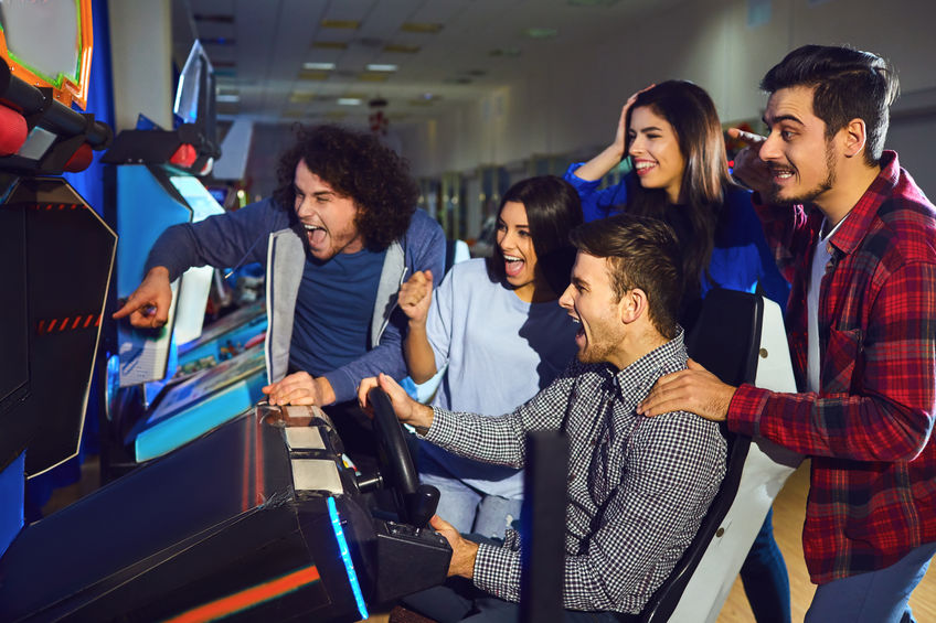 A group of friends playing arcade machine.