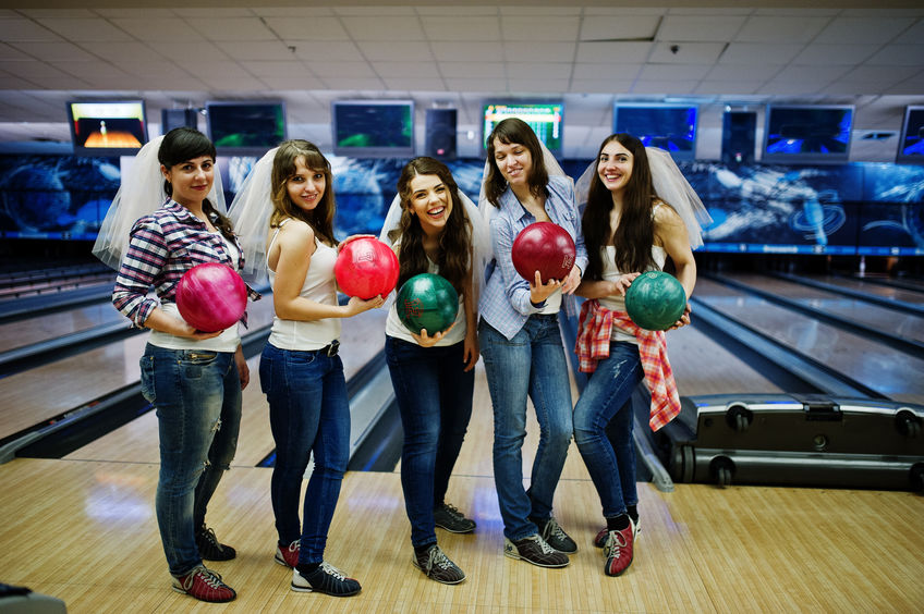 Group of six girls wit bowling balls at hen party on bowling clu